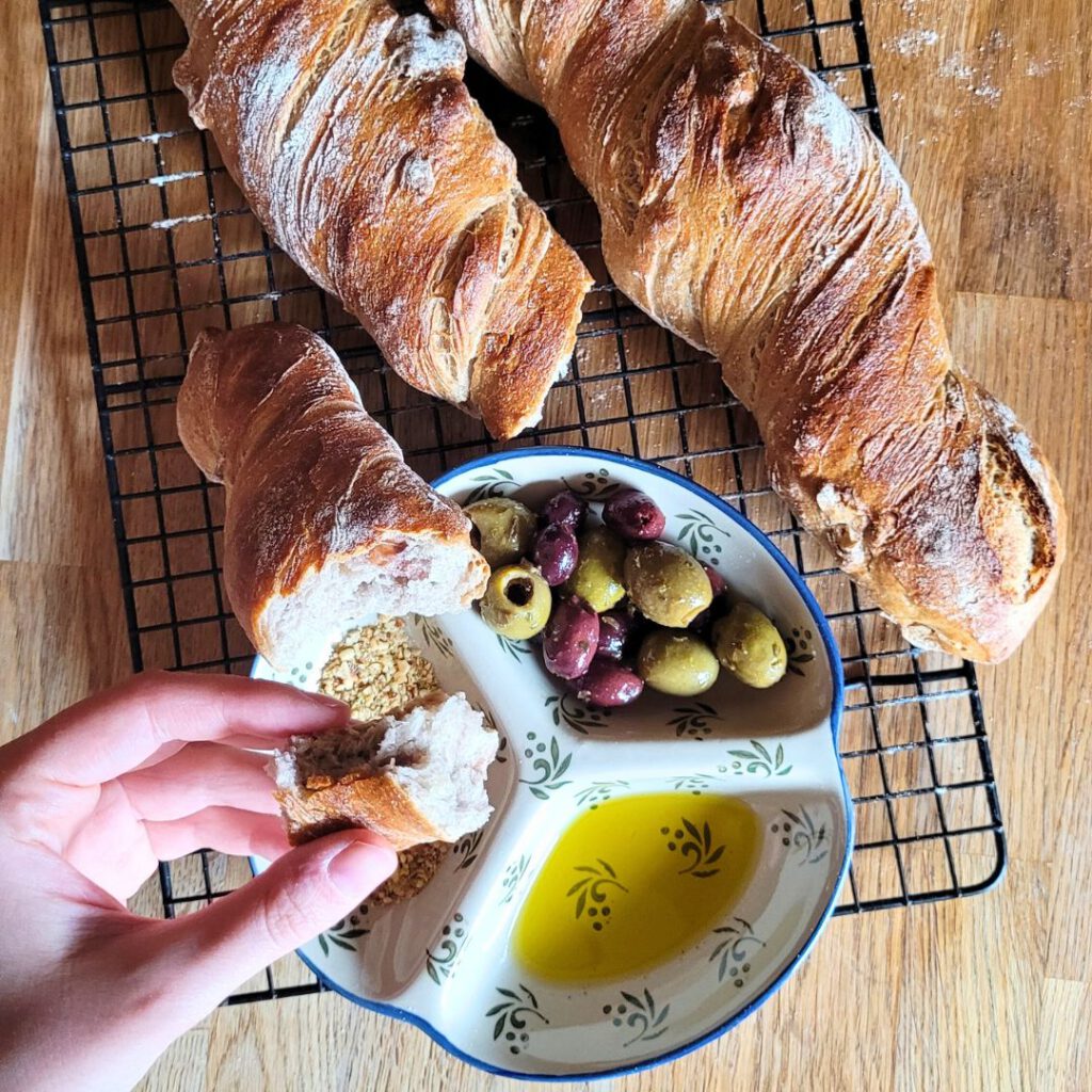 Rustikales Wurzelbrot mit Sauerteig und ein Teller mit Oliven