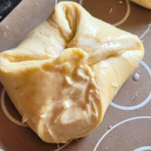 Die Quarktaschen auf ein Backblech legen, mit Milch, Wasser oder Ei bestreichen und abgedeckt für zwei bis drei Stunden ruhen lassen – je nach Raumtemperatur.
