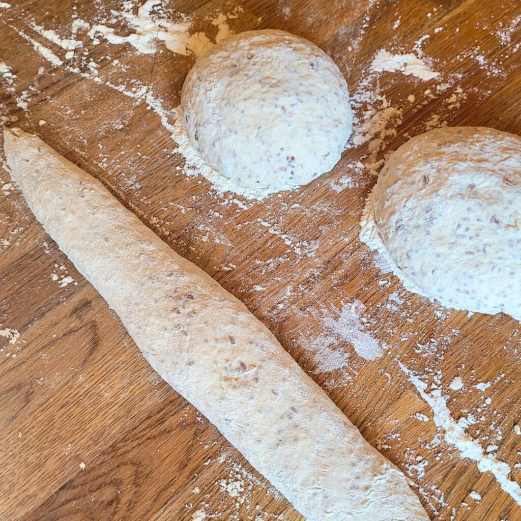 Die Teiglinge mit dem Schluss nach oben drehen und unter Spannung zu länglichen Baguettes aufrollen.