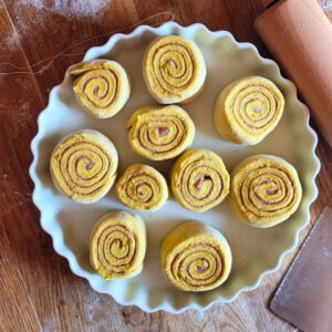 Die Zimtschnecken mit etwas Abstand zueinander in eine gefettete Ofenform legen