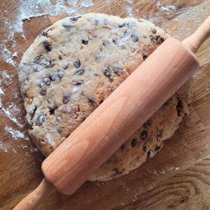 Für einen gewickelten Stollen wird die Rolle mit einem Nudelholz von der Mitte ausgerollt. Die Räder der Längsseiten bleiben dabei leicht verdickt.