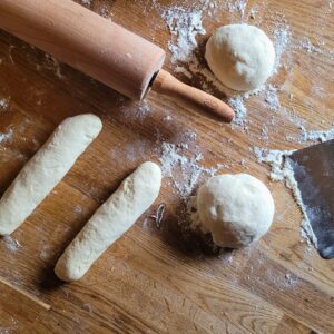 Danach mit einem Nudelholz ausrollen und unter Spannung aufrollen. Die Enden fest verschließen und die geformten Hot Dog Brötchen auf ein Backblech legen.